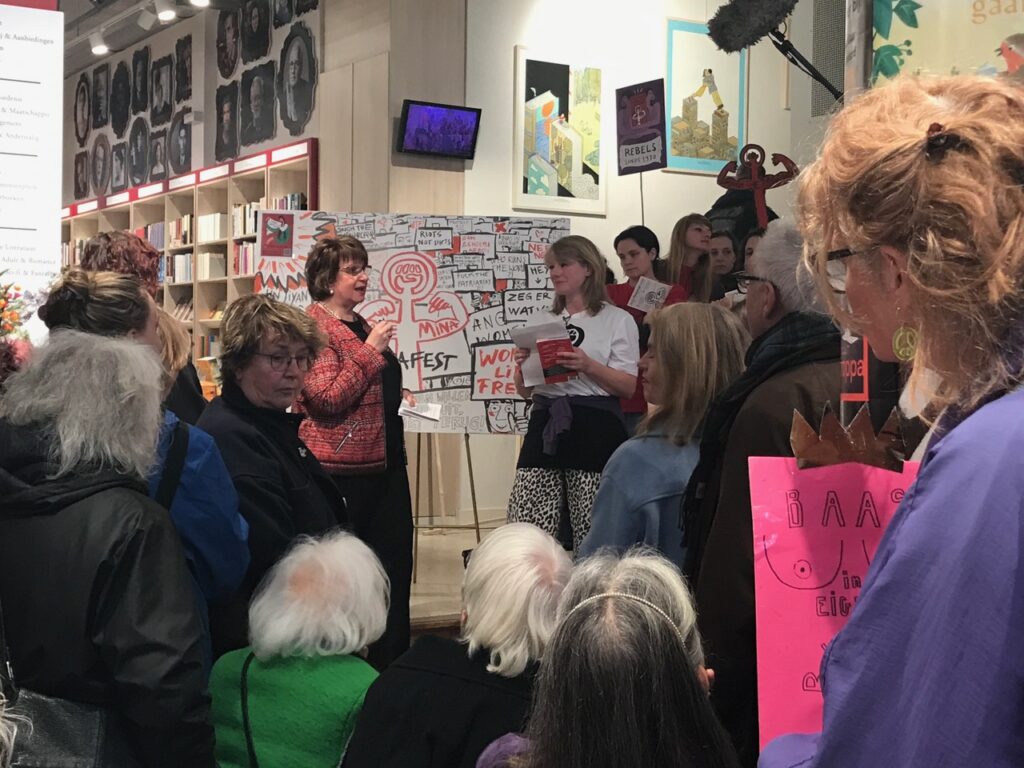Overhandiging 1e exemplaar Minafest aan Mariëtte Hamer, regeringscommissaris seksueel grensoverschrijdend gedrag en seksueel geweld, op Internationale Vrouwendag 8 maart 2026 bij boekhandel Scheltema  (foto Dunya Verwey)